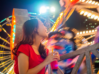 happy asia mother and daughter have fun in amusement carnival park with farris wheel and carousel background