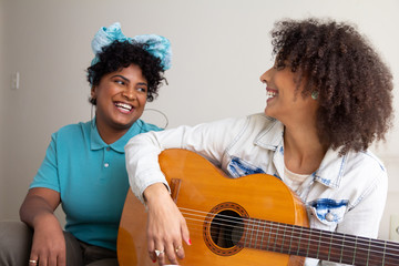 Diverse of college students playing guitar and singing together in small apartment at living room. Fun and happy times.