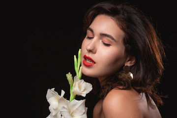Beautiful woman with bright makeup posing isolated over black background with white flower.