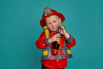 A little boy in a fireman costume plays and dreams of putting out the fire. Fireman on a blue background.