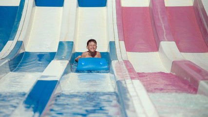  Caucasian boy in waterpark in . He sliding down colorful waterslide..