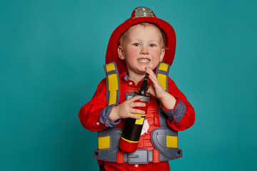 A little boy in a fireman costume plays and dreams of putting out the fire. Fireman on a blue...