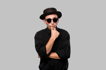 Fototapeta premium Stylish handsome man a black shirt and pork pie hat isolated over grey background