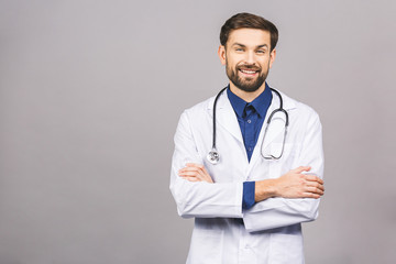Portrait of cheerful smiling young doctor with stethoscope over neck in medical coat standing against isolated gray background.