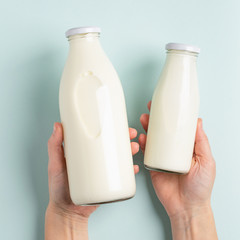 Female hand holds milk or white milk drink in a glass bottle on white background. Healthy eating...
