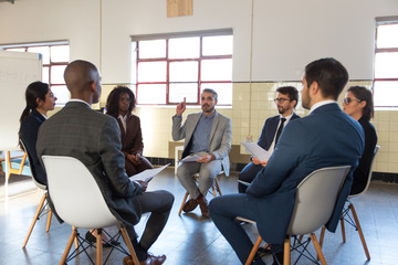 Focused colleagues discussing new information. Focused colleagues sitting in chairs with paper...