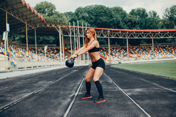 Sports girl at the stadium. Beautiful girl doing sports. The girl raises the weight