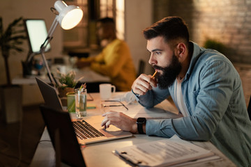 Young businessman working late on laptop in the office.