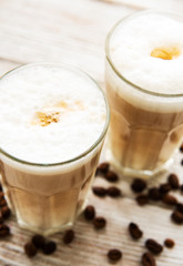 Two glasses of latte coffee and coffee beans