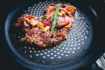 Cooked beef steak with rosemary and garlic inside iron skillet