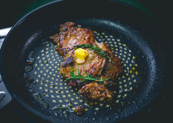 Cooked beef steak with rosemary and garlic inside iron skillet