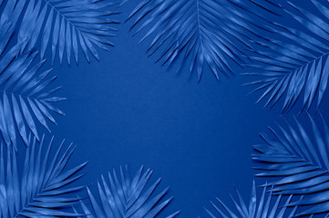 Fototapeta na wymiar Tropical palm leaves on blue background. Flat lay, top view, copy space. Summer background, nature. Creative minimal background with tropical leaves. Leaf pattern. Color of the year 2020 classic blue