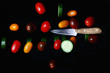 hand with a kitchen knife on a background of vegetables