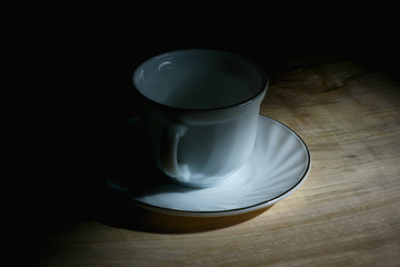 white tea cup on a saucer in a ray of sunlight