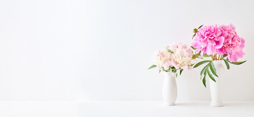 Home interior with decor elements. Pink peonies in a vase on a white background