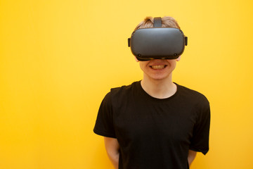 happy guy with VR glasses on a yellow background, using modern virtual reality gadgets