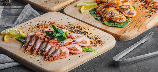 Raw and fried shrimps with lemon on wooden board
