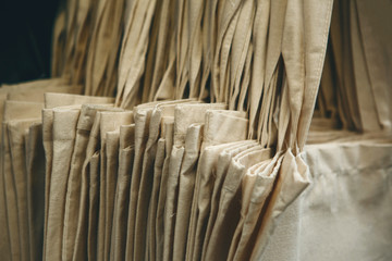 Close-up of a lot of trendy eco-friendly canvas bags hanging in a row