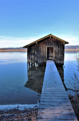 Idyllic sunny winter day at the bavarian Lake Kochelsee (Lake Kochel) at Kochel am See. View to the beautiful wooden boathuts