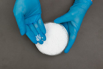 Plastic granules . Polypropylene, polyethylene pellets in hands with gloves. Quality control of...
