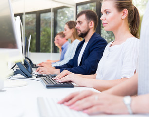 Focused colleagues working at computers in modern coworking space