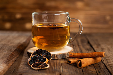  mug with tea on a wooden background with cinnamon, dry orange and star anise.