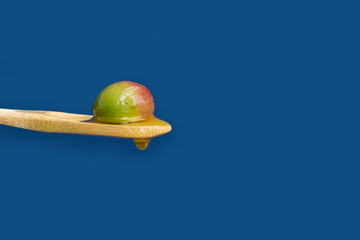 Mature olive on a wooden spoon on a blue background