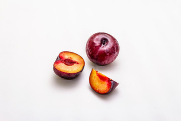 Ripe large purple plums. Fresh whole fruits, half sliced, seeds. Isolated on white background