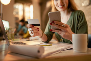 Close-up of businesswoman shopping online with credit card and smart phone.