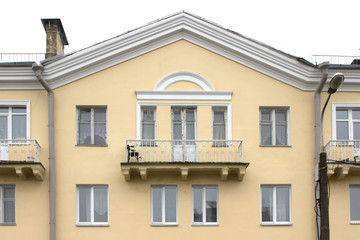 Fototapeta na wymiar wide balcony of the old yellow building. Triangular roof, white frames, minimalism