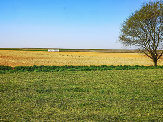 Spring landscape of the Haspengouw or Hesbaye region in Belgium with large white name sign in the middle of the fields