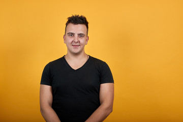 Handsome caucasian young woman wearing black shirt isolated on orange background in studio looking at camera, smiling. People sincere emotions, lifestyle concept.