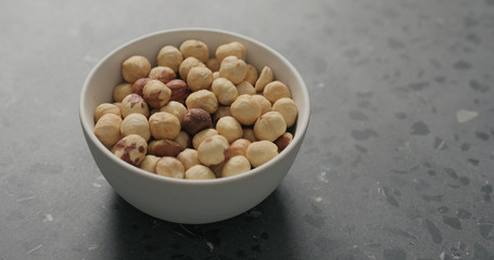 roasted hazelnuts in white bowl on terrazzo countertop