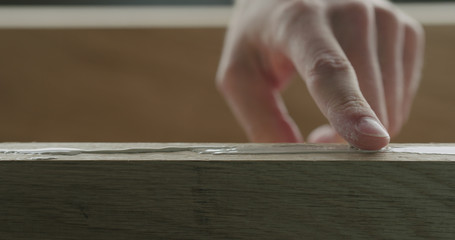 closeup man spreading wood glue on oak board with finger