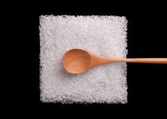 Salt with large crystals. Sea salt. Salt crystals on a black background. A pile of salt in the shape of a square with a wooden spoon.