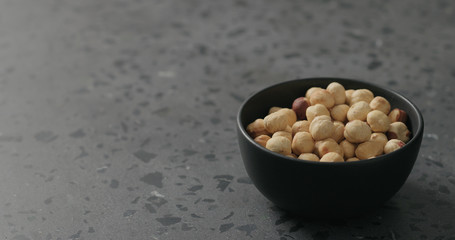 roasted hazelnuts in black bowl on terrazzo countertop