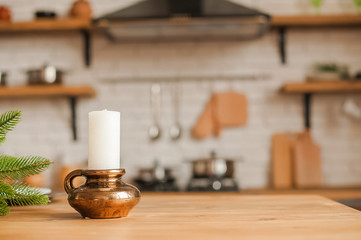 Christmas kitchen decor and copy space. Rustic kitchen in defocus. Table and candle in a bronze candlestick in focus.