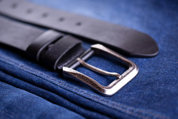 Leather belt lies on denim. Belt accessory wardrobe. Beautiful wide belt and jeans close-up.