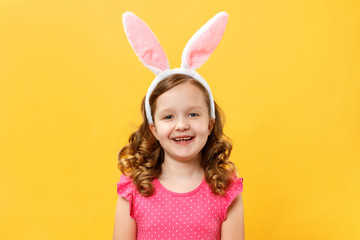 Obraz na płótnie Canvas Happy cute little girl in easter bunny ears. Child close-up on a yellow background color