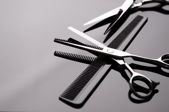 Barber scissors close-up. Barber scissors and a comb lie on the mirror surface of the table. Hairdresser tool.