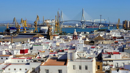  Panorama von Cadiz mit vielen weißen Häusern, der Hafenanlage und dem Meer unter blauem Himmel © globetrotter1
