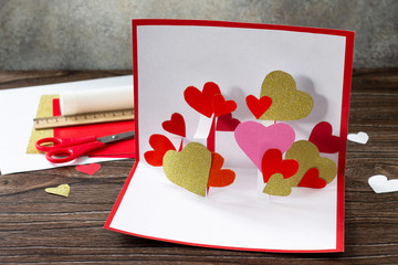 Valentine's Day greeting card or birthday present on wooden table. Children's art project crafts...