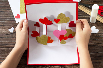 The child holds a Valentine's Day greeting card or birthday present. Children's art project crafts...