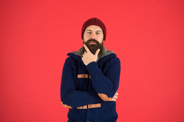 Winter menswear. Man bearded warm jumper and hat red background. Winter season menswear. Personal stylist. Warm and comfortable. Fashion menswear shop. Masculine clothes concept. Think and decide