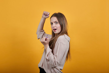 Happy caucasian brunette woman in fashion pastel shirt doing winner gesture, smiling isolated on...