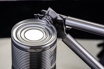 a handmade can opener from Finland next to a can on a black background