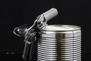 a handmade can opener from Finland next to a can on a black background