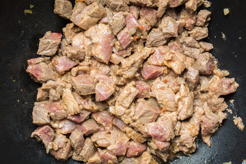 Fresh pieces of red veal tenderloin with onions are roasted in large cauldron for pilaf.