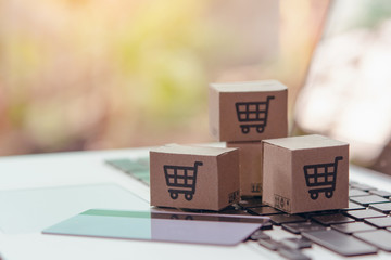 Online shopping - Paper cartons or parcel with a shopping cart logo and credit card on a laptop keyboard. Shopping service on The online web and offers home delivery...