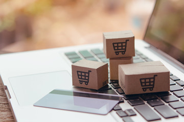  Shopping online. Credit card and cardboard box with a shopping cart logo on laptop keyboard....
